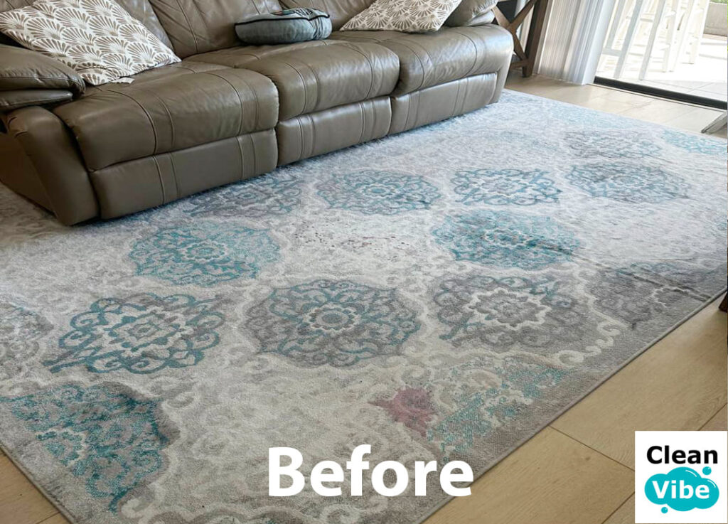 Gray and blue patterned rug before cleaning near leather sofa